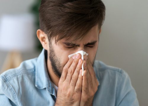 Man with a cold blowing his nose