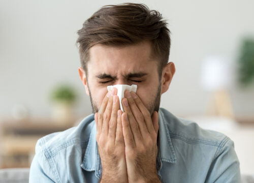 Photo of a man with sinusitis blowing his nose with a tissue