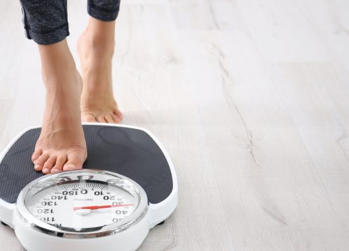Woman stepping on a scale to check for weight loss