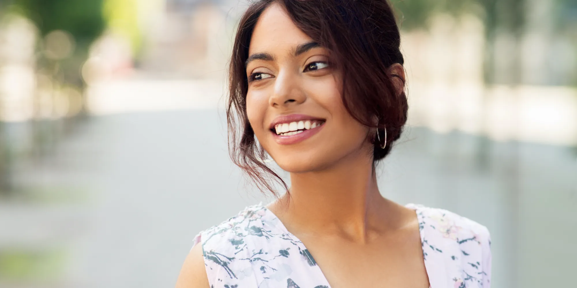 Smiling woman with dark hair standing outside in a sundress