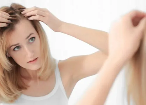 Photo of a woman checking her scalp in the mirror for hair growth