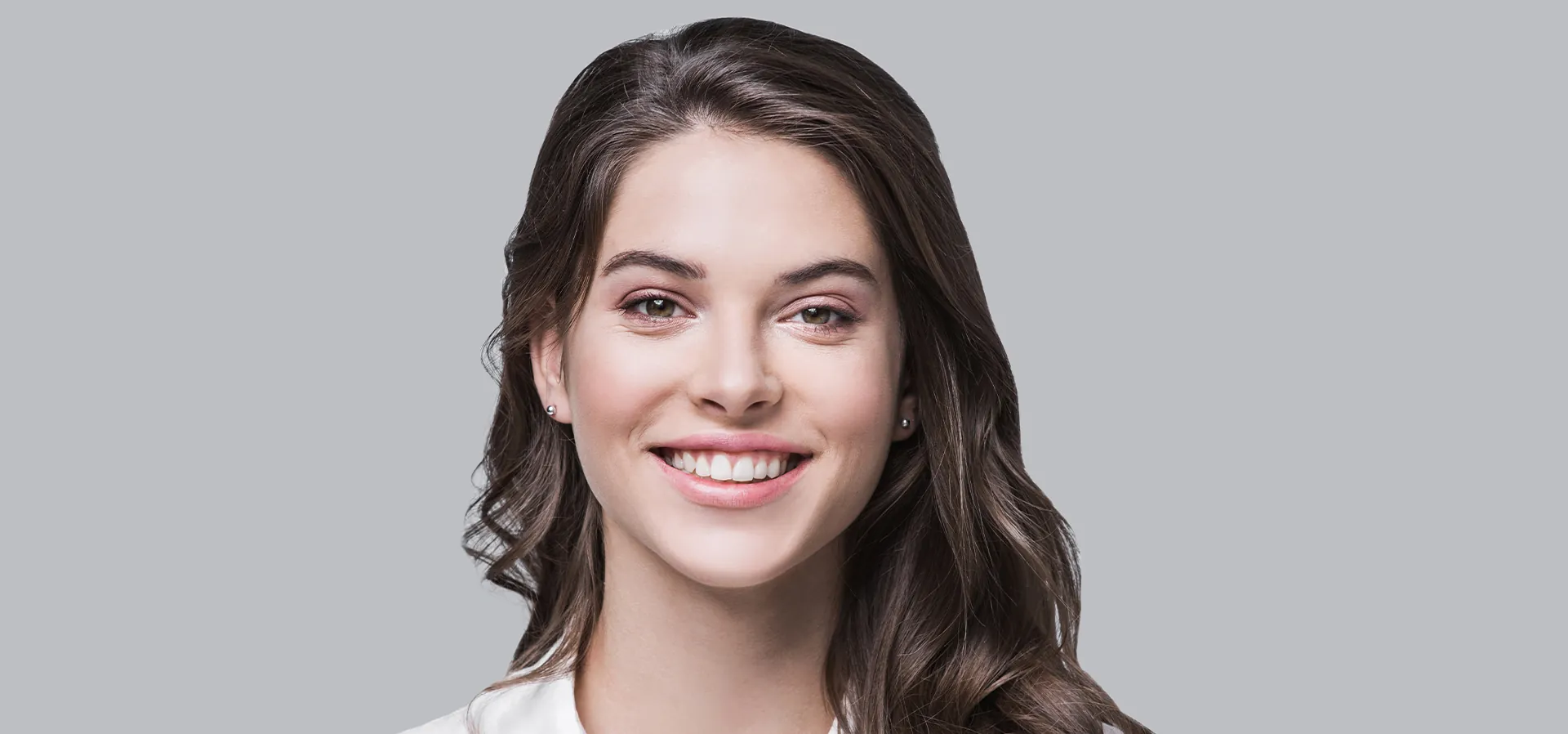 Photo of a young brunette woman wearing earrings and a white shirt