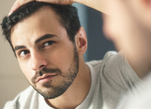 Photo of a man checking his hairline in the mirror